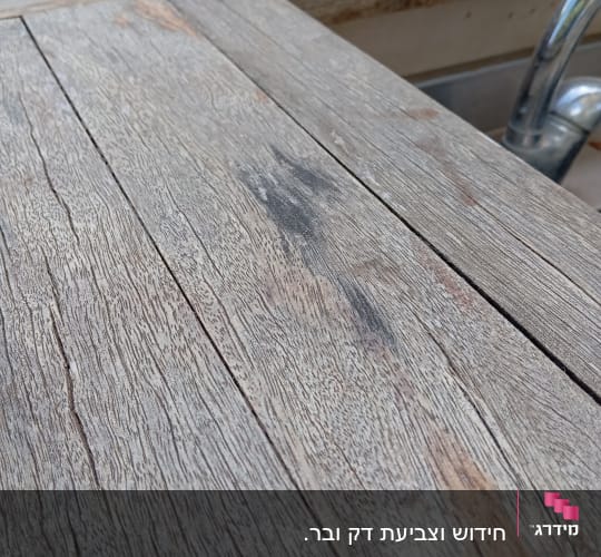 משטח עץ מחוספס ליד ברז מתכת